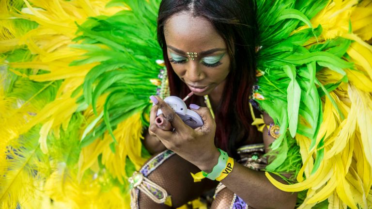 A costumed dancer puts on makeup as she gets ready to march in the West Indian Day Parade along Eastern Parkway in Brooklyn on Monday, Sept. 5, 2016.