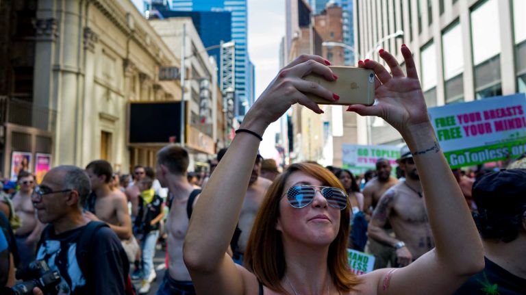 A woman photographs the GoTopless Pride Parade on Sunday, Aug. 28, 2016, in Manhattan.