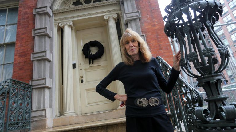 Pi Gardiner, executive director of the Merchant's House Museum, stands on the front stairs of the house on E. 4th Street, with a black wreath on the door behind her, on Oct. 11.