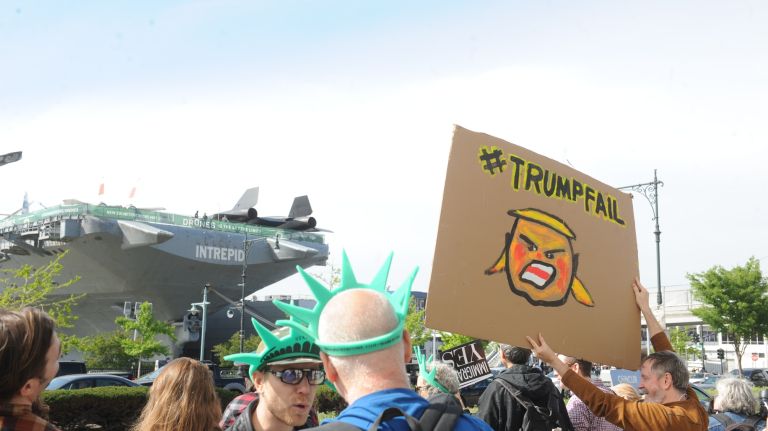 Protesters stand across the from Intrepid Sea, Air & Space Museum, seen in the background, in Manhattan while waiting for President Donald Trump's arrival in Manhattan on Thursday, May 4, 2017. 