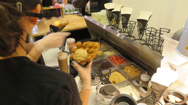 The freshly cooked waffle is carefully folded and placed in a temporary stand, with a scoop of ice cream. 