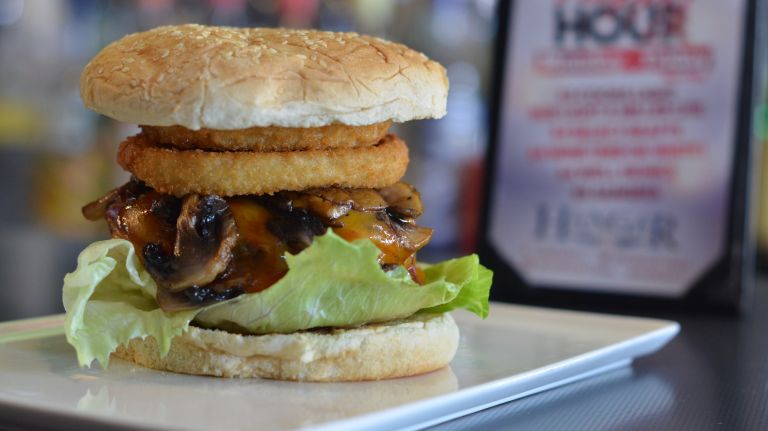 Where to eat in Kew Gardens, Queens: Restaurants, bakeries and more 8 Better wear your wings - this bar and restaurant comes complete with a fun airplane theme. Hangar 11 Bar & Grill offers well-priced drinks, burgers (pictured is the Austin, with onion rings and barbecue sauce), sandwiches, salads and more - and trust us, it's much better than airplane food. Come in for a landing at Hangar 11 by visiting 119-11 Metropolitan Ave.