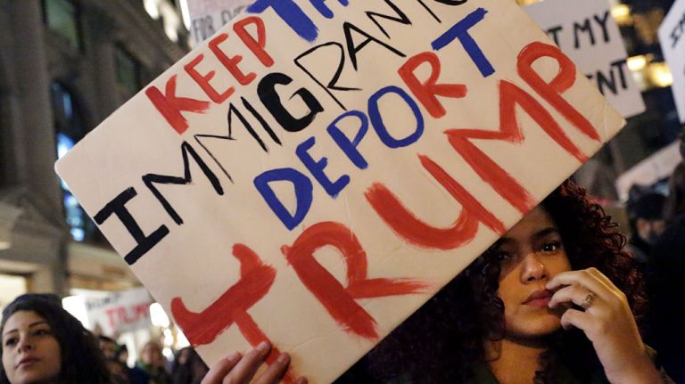 A woman holds a sign reading 