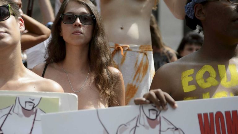 Participants, some topless, hold a rally in Bryant Park during an event marking International Go Topless Day in Manhattan on Sunday, August 23, 2015. The event was independent of, but coincide with, the apparent proliferation topless tip seeking women in Times Square.