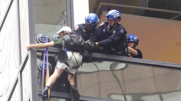A man scaling the all-glass face of Trump Tower in New York City using suction cups is grabbed by police officers on Wednesday, Aug. 10, 2016.