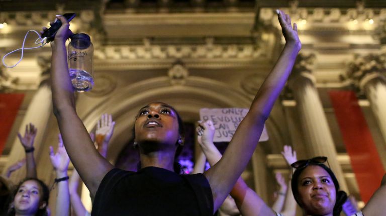 Demonstrators raise their arms during a march through Manhattan on July 7, 2016, to protest the deaths of two black men at the hands of police in Louisiana and Minnesota. 