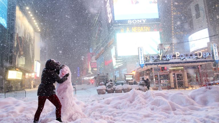 A woman decorates a snowman in Times Square as all cars but emergency vehicles are banned from driving on the road on Jan. 23, 2016, in New York City.