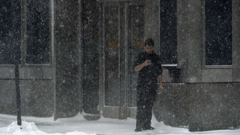 A restaurant worker on 3rd Avenue in Manhattan takes a break outside on Saturday, Jan. 23, 2016. A snow emergency is currently in effect as accumulations in the city could top out at over a foot before the storm is expected to end this evening.