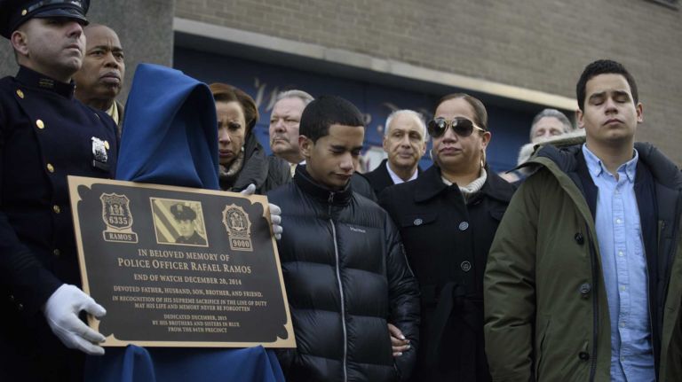 Justin Ramos, right, Maritza Ramos, second from right, and Jaden Ramos, center, the wife and children of slain NYPD Detective Rafael Ramos attend a memorial plaque dedication ceremony honoring Detective Ramos and Detective WenJian Liu at the 84th Precinct in Brooklyn on Sunday, Dec. 20, 2015. Liu and Ramos were shot and while in a squad car last December.
