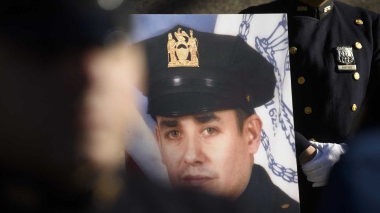 Members of the New York Police Department hold a ceremony in front of the 84th Precinct in Brooklyn to mark the one year anniversary of the murders of NYPD detective Wenjian Liu and NYPD Detective Rafael Ramos, scene here, Sunday, Dec. 20, 2015. Liu and Ramos were shot and while in a squad car last December.