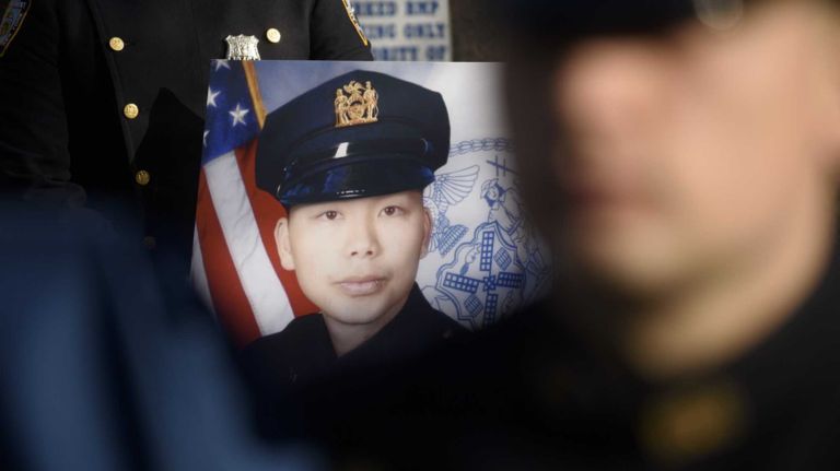 Members of the New York Police Department hold a ceremony in front of the 84th Precinct in Brooklyn to mark the one year anniversary of the murders of NYPD detective Wenjian Liu, scene here, and NYPD Detective Rafael Ramos, Sunday, Dec. 20, 2015. Liu and Ramos were shot and while in a squad car last December.