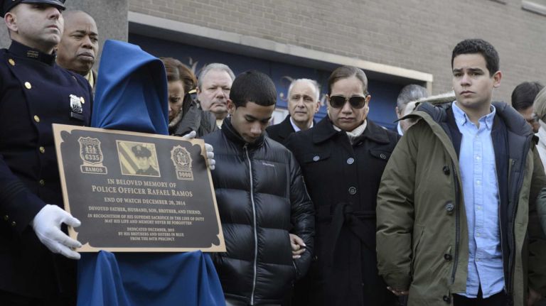Justin Ramos, right, Maritza Ramos, second from right, and Jaden Ramos, center, the wife and children of slain NYPD Detective Rafael Ramos attend a memorial plaque dedication ceremony honoring Detective Ramos and Detective WenJian Liu at the 84th Precinct in Brooklyn on Sunday, Dec. 20, 2015. Liu and Ramos were shot and while in a squad car last December.