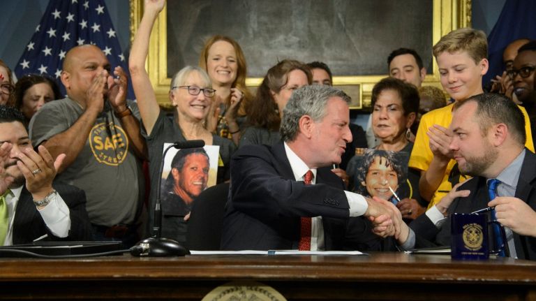 NYC’s speed cameras back on and expanded in time for start of school year 1 Mayor Bill de Blasio, center, shakes hands with City Council Speaker Corey Johnson as family members and friends who lost loved ones to motorists cheer after the mayor signed a bill in Manhattan Tuesday that preserves and expands the use of speed cameras near schools.