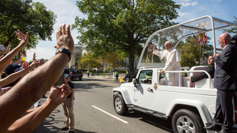 Pope Francis waves to the crowd as he rides in a popemobile along a parade route around the National Mall on September 23, 2015 in Washington, DC.