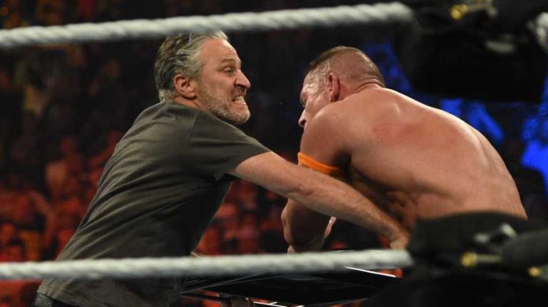 Jon Stewart hits United States champion John Cena with a chair during the Title vs. Title match against WWE world heavyweight champion Seth Rollins during the SummerSlam 2015 at Barclays Center on Sunday, Aug. 23, 2015.