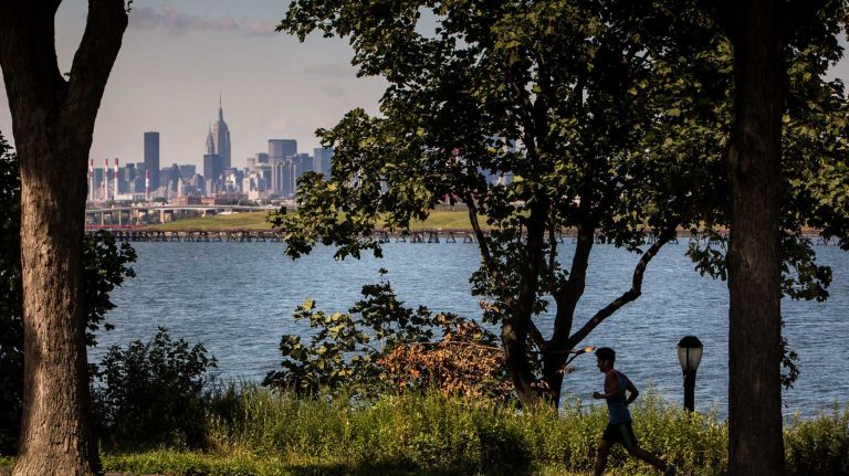 College Point, Queens 21 A jogger in MacNeil Park with a view of the New York City skyline in the background. City Living in the neighborhood of College Point in Queens.August 7, 2015