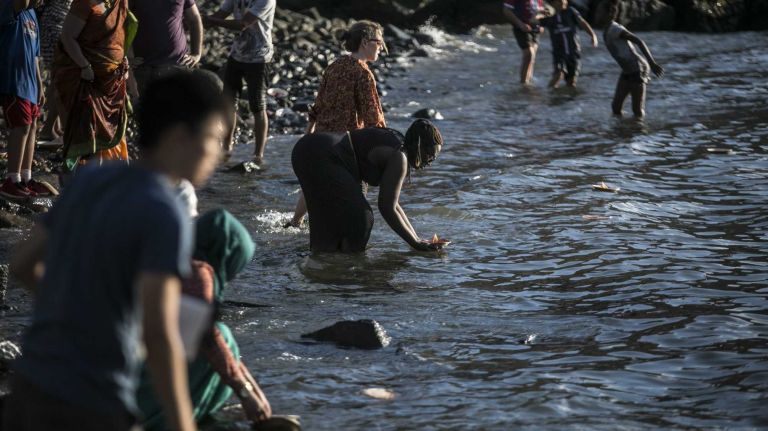 People place candles in the East River at a Hindu candle-lighting ceremony at Brooklyn Bridge Park on Aug. 1, 2015.