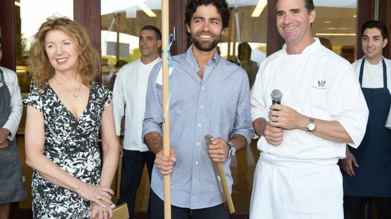 Artist April Gornik joins chef Kerry Heffernan as he presents actor Adrian Grenier, center, with a clam rake for his birthday at the South Fork Natural History Museum's 26th Annual Summer Gala on July 11, 2015, in Bridgehampton.
