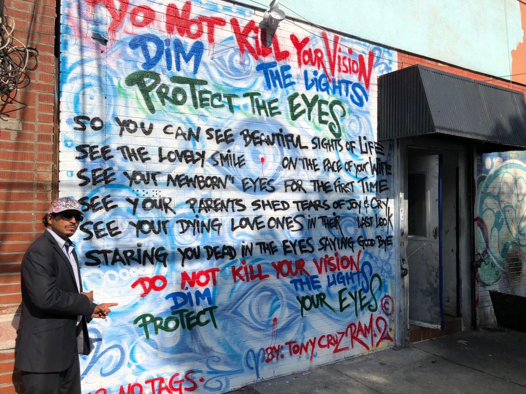 Tony Cruz with his vision awareness mural on Westchester Avenue in the Bronx.