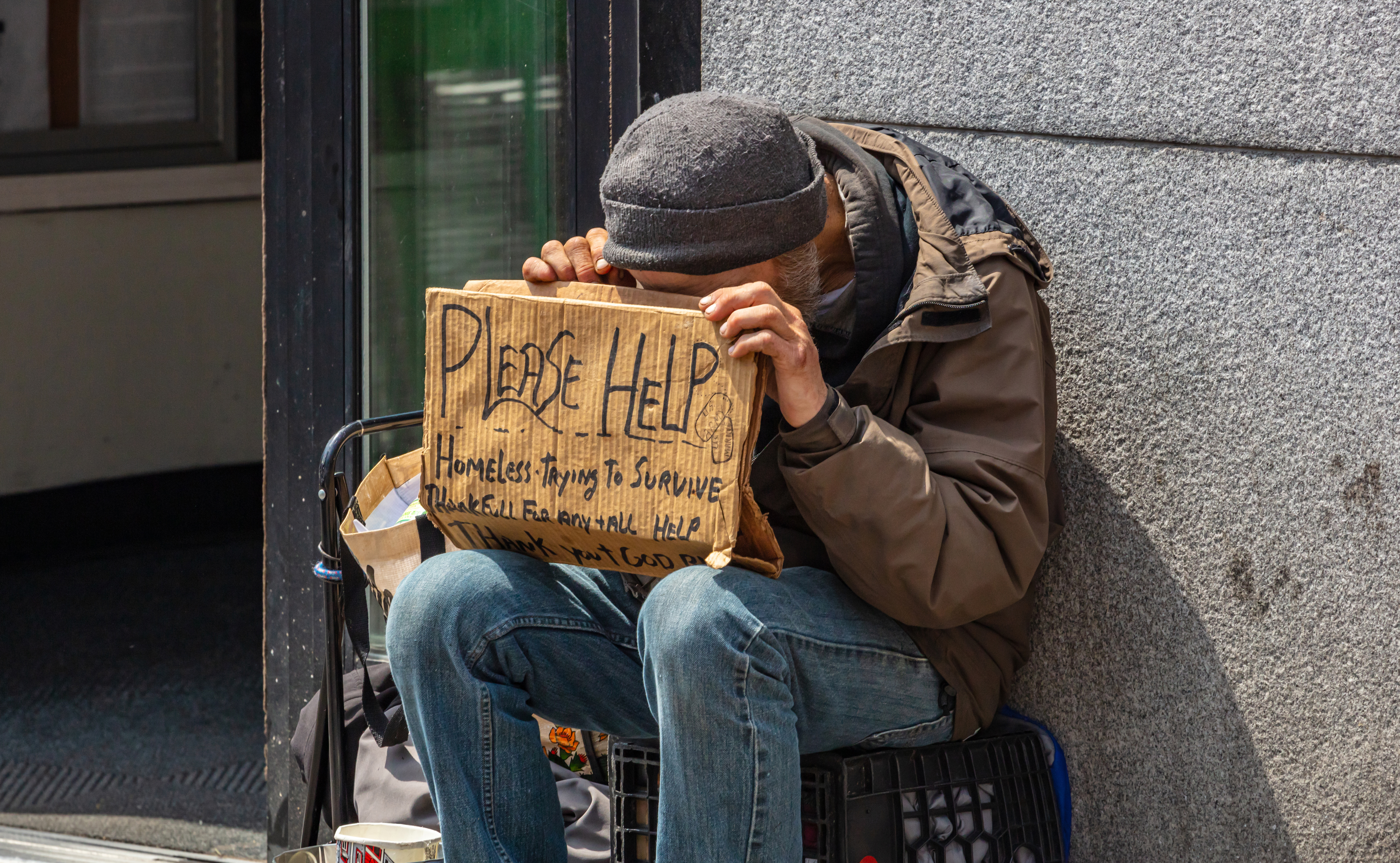 New York, Manhattan downtown. Homeless man holding a cardboard sign, begging