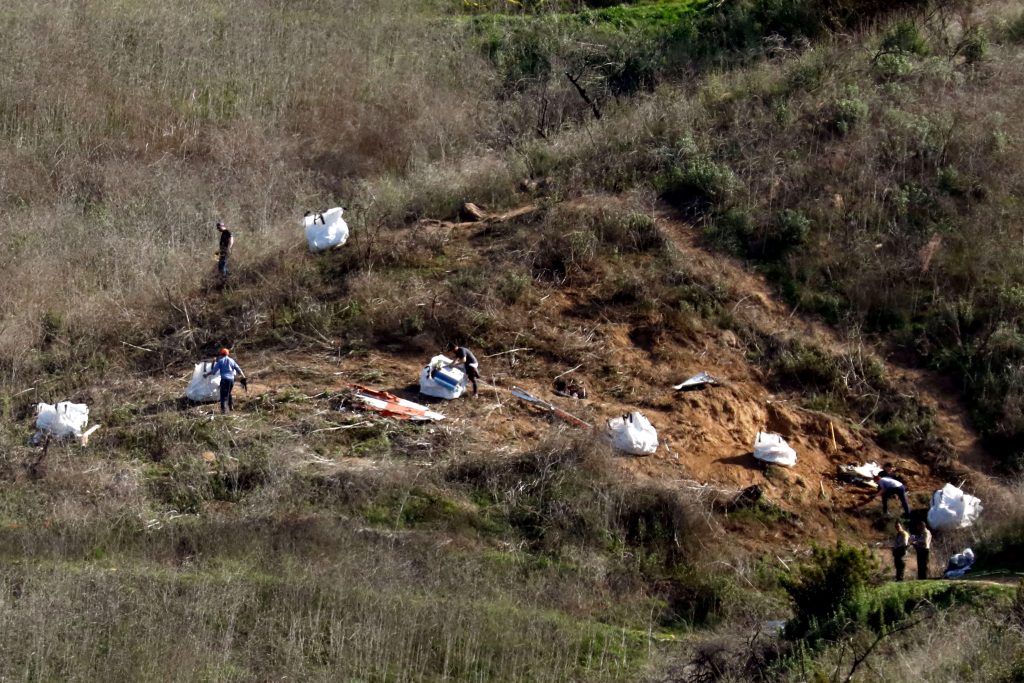 Personnel collect debris while working with investigators at the helicopter crash site of NBA star Kobe Bryant in Calabasas, California