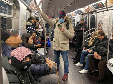 A man with a face mask rides the subway in the Queens borough of New York Cit