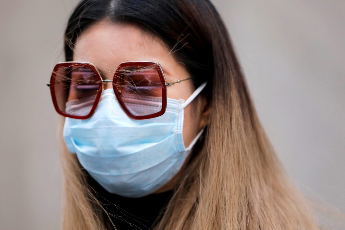 FILE PHOTO: A woman in a face mask walks in the downtown area of Manhattan, New York City, after further cases of coronavirus were confirmed in New York