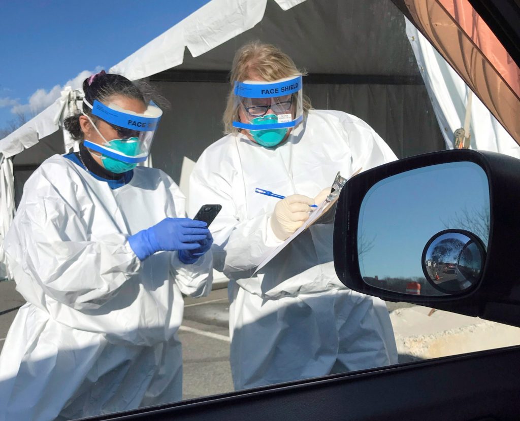 Workers in protective clothing record details during drive through coronavirus testing in New Rochelle