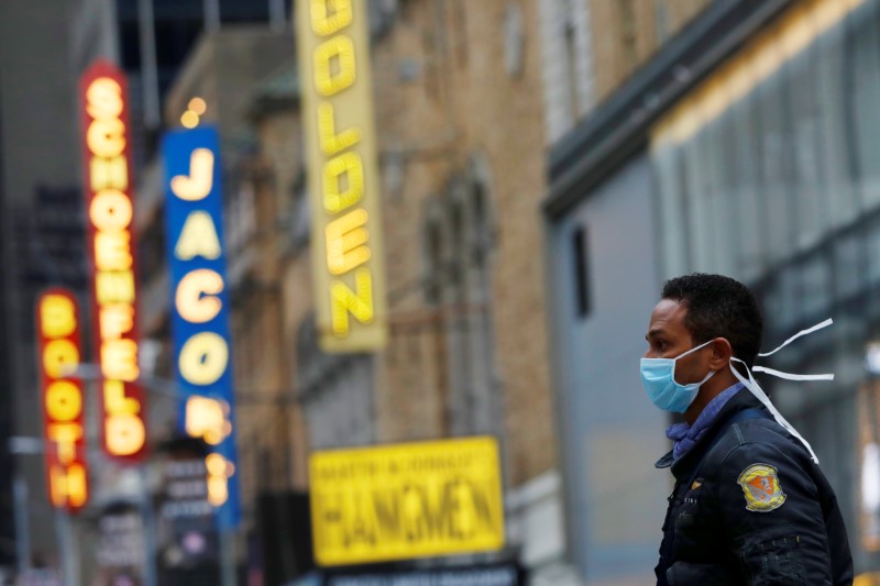 A man in a surgical mask walks through Manhattan’s Broadway Theatre district after Broadway shows announced they will cancel performances due to the coronavirus outbreak in Manhattan, New York City