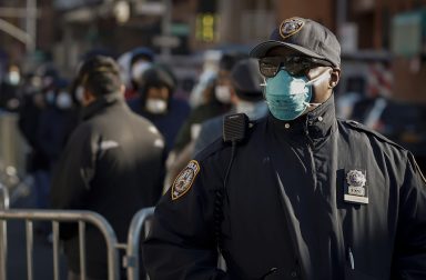A New York City Police officer (NYPD) wears protective gear, while monitoring people waiting in line to be tested for coronavirus disease (COVID-19) outside Elmhurst Hospital Center in the Queens borough of New York