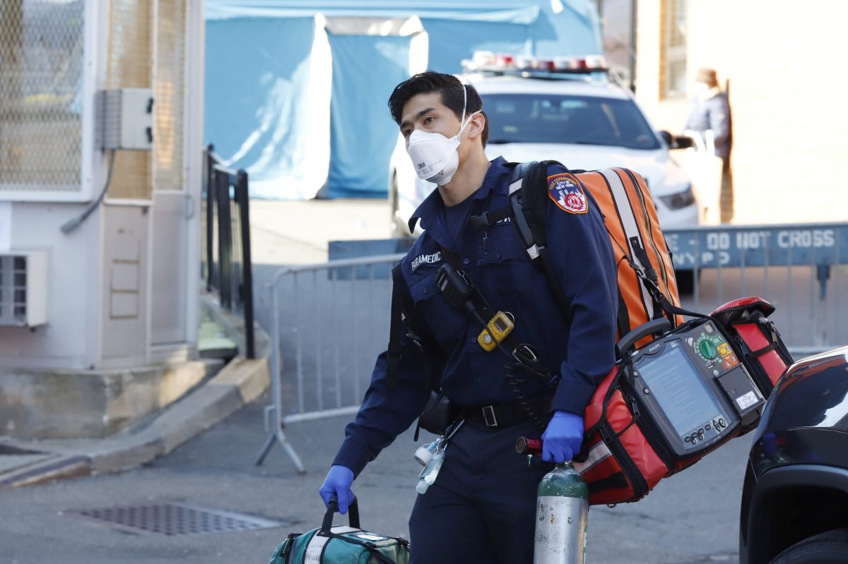 An emergency medical technician carries equipment near where people are waiting to be tested for coronavirus disease (COVID-19) outside Elmhurst Hospital Center in the Queens borough of New York City