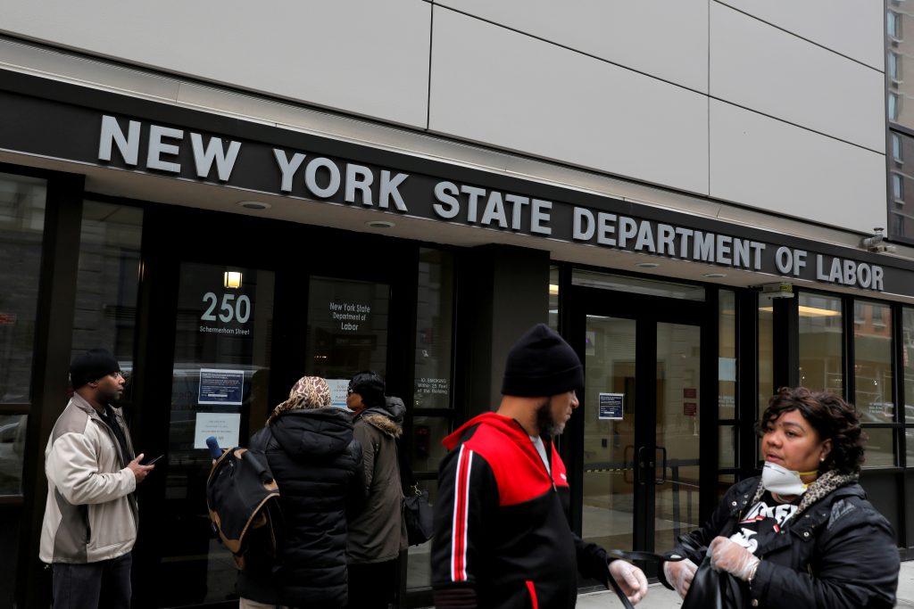 FILE PHOTO: People gather at the entrance for the New York State Department of Labor offices, which closed to the public due to the coronavirus disease (COVID-19) outbreak in the Brooklyn borough of New York City