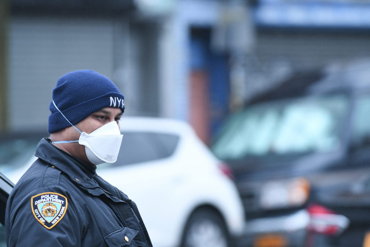 A Cop from the 67 Precinct protects himself against Coronavirus by wearing a mask at the scene of a shooting on  East 96 Street and Rutland Road in East Flatbush, Brooklyn on Sunday, March 29th.