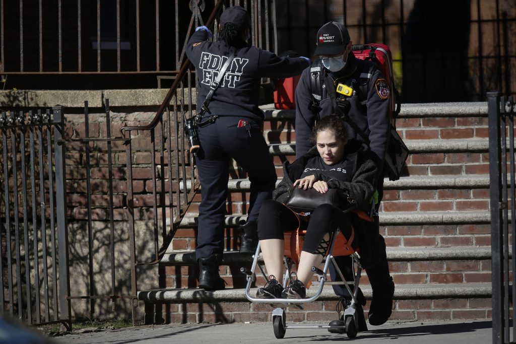 Emergency Medical Technicians (EMT) wearing protective gear wheel sick patient to ambulance during the outbreak of coronavirus disease (COVID-19) in New York