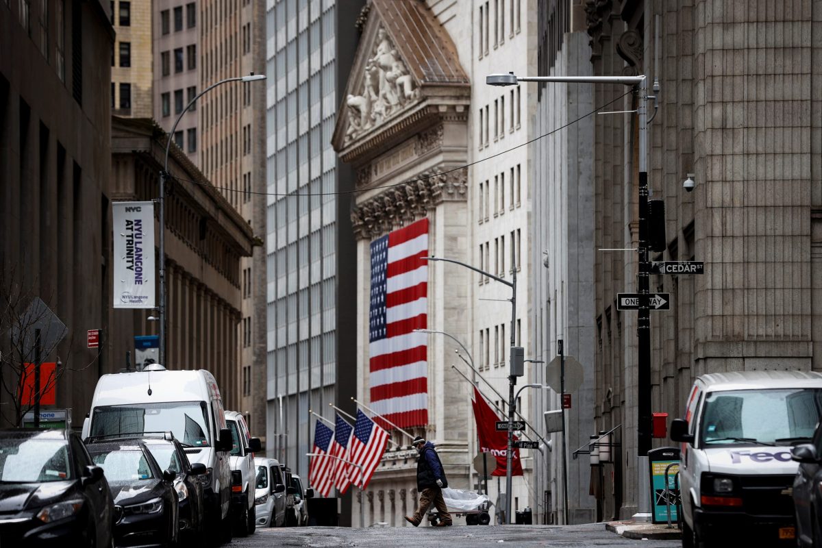A man crosses a nearly deserted Nassau street in front of the New York Stock Exchange (NYSE) in the financial district of lower Manhattan in New York