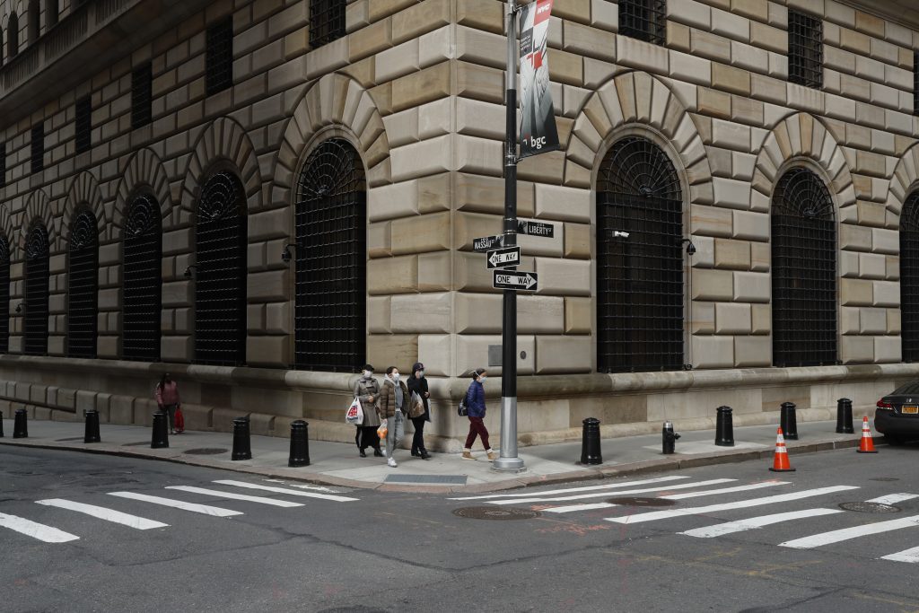 People walk wearing masks outside The Federal Reserve Bank of New York in New York