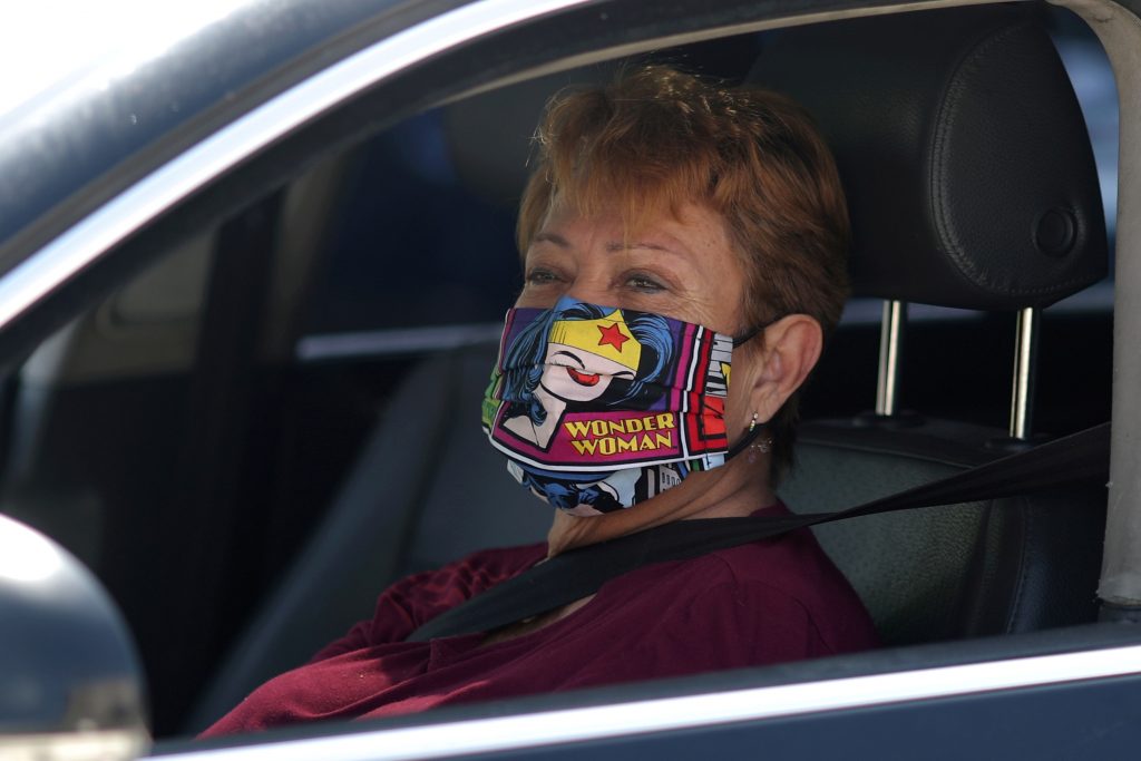 FILE PHOTO: A woman wears a Wonder Woman mask as she waits in line at a Los Angeles Food Bank drive-through food giveaway as the global outbreak of coronavirus disease (COVID-19) continues, in Los Angeles