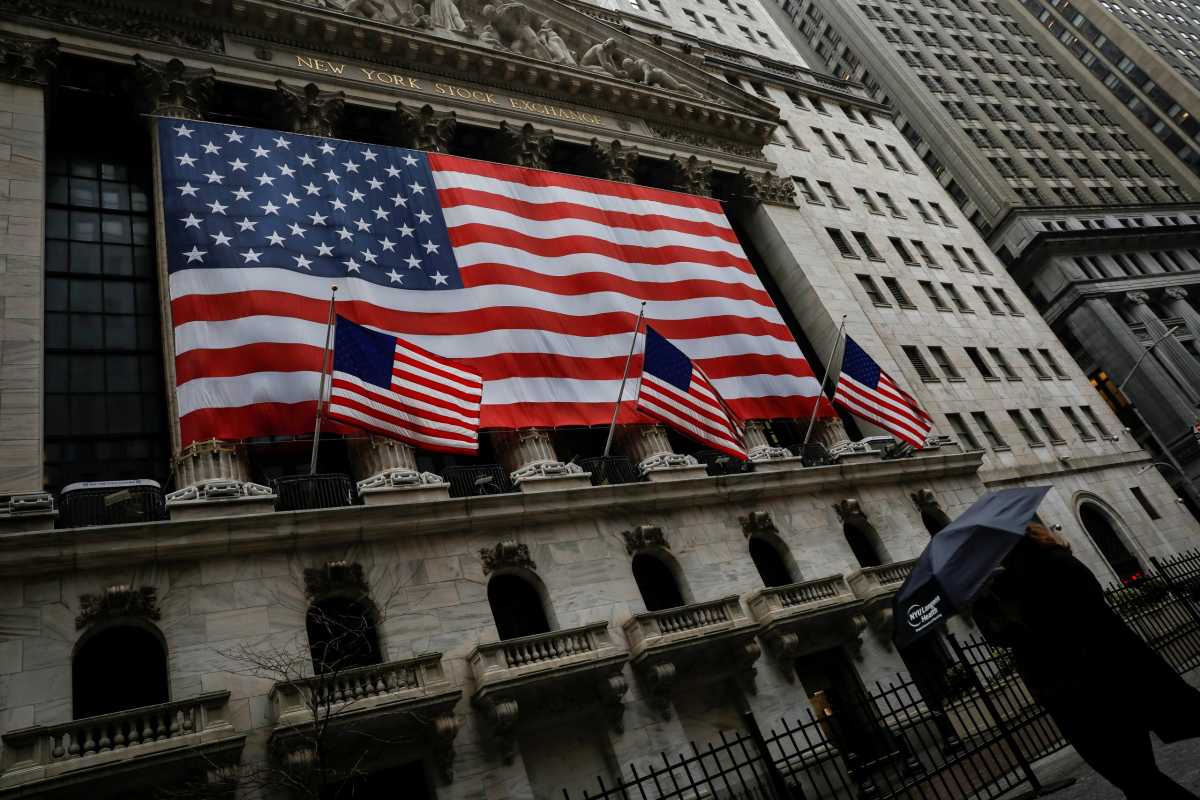 A woman walks in the rain outside the New York Stock Exchange (NYSE) in the financial district of lower Manhattan during outbreak of coronavirus disease (COVID-19) in New York