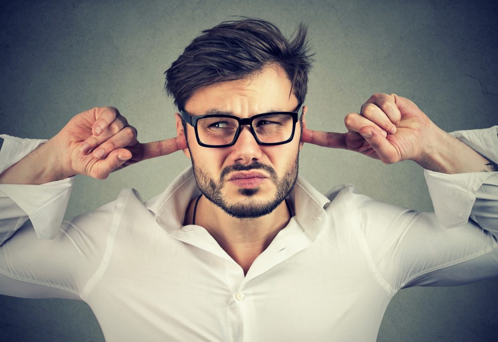 Annoyed man covering ears
