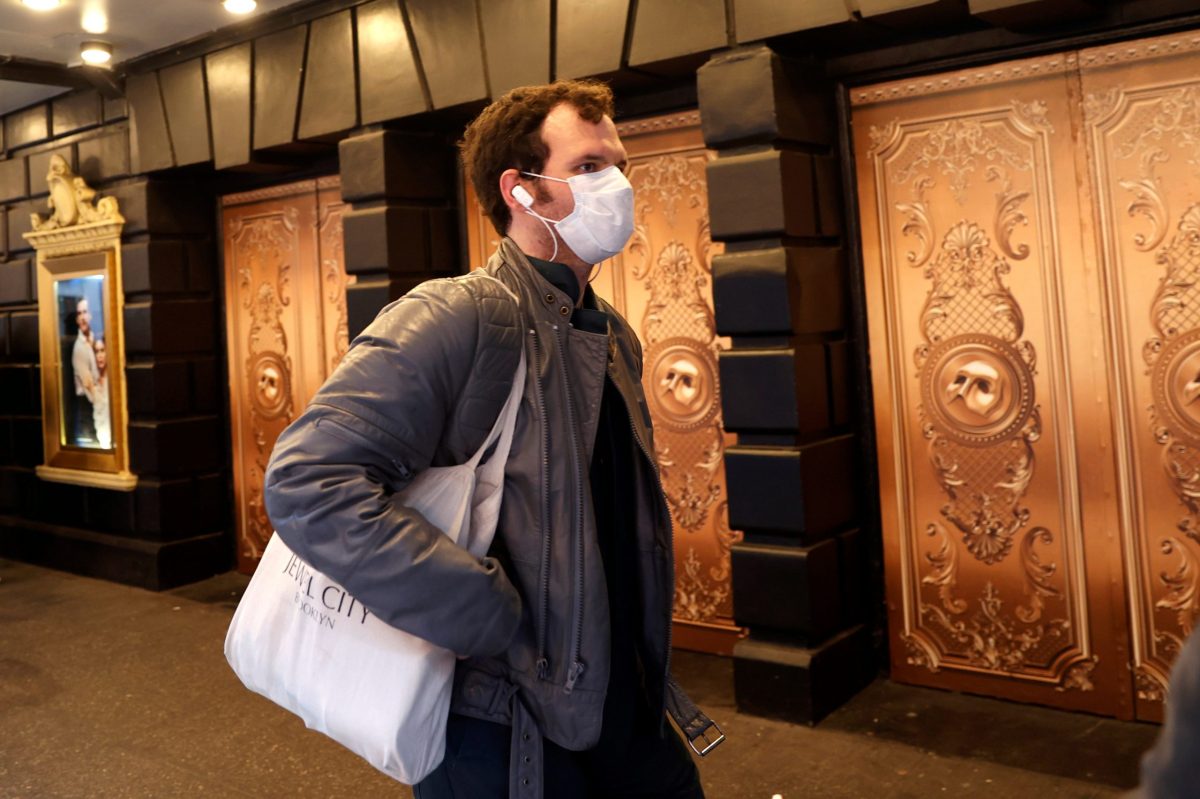 FILE PHOTO: A man in a protective mask walks past a closed theatre after it was announced that Broadway shows will cancel performances due to the coronavirus outbreak in New York