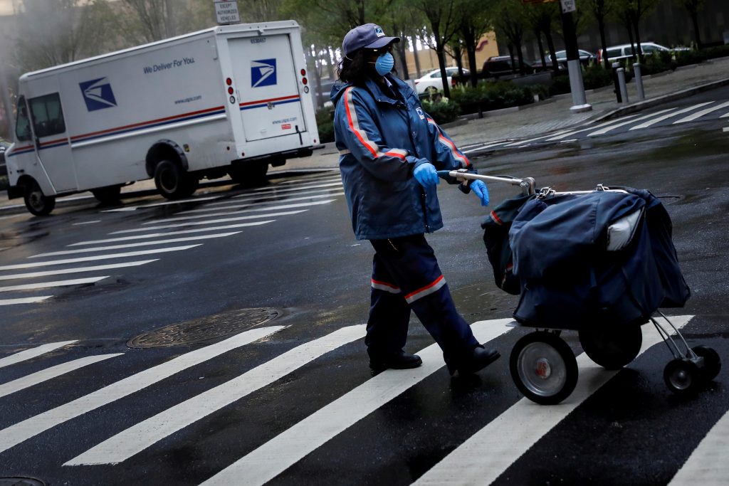 A United States Postal Service (USPS) worker works in the rain in Manhattan during outbreak of coronavirus disease (COVID-19) in New York