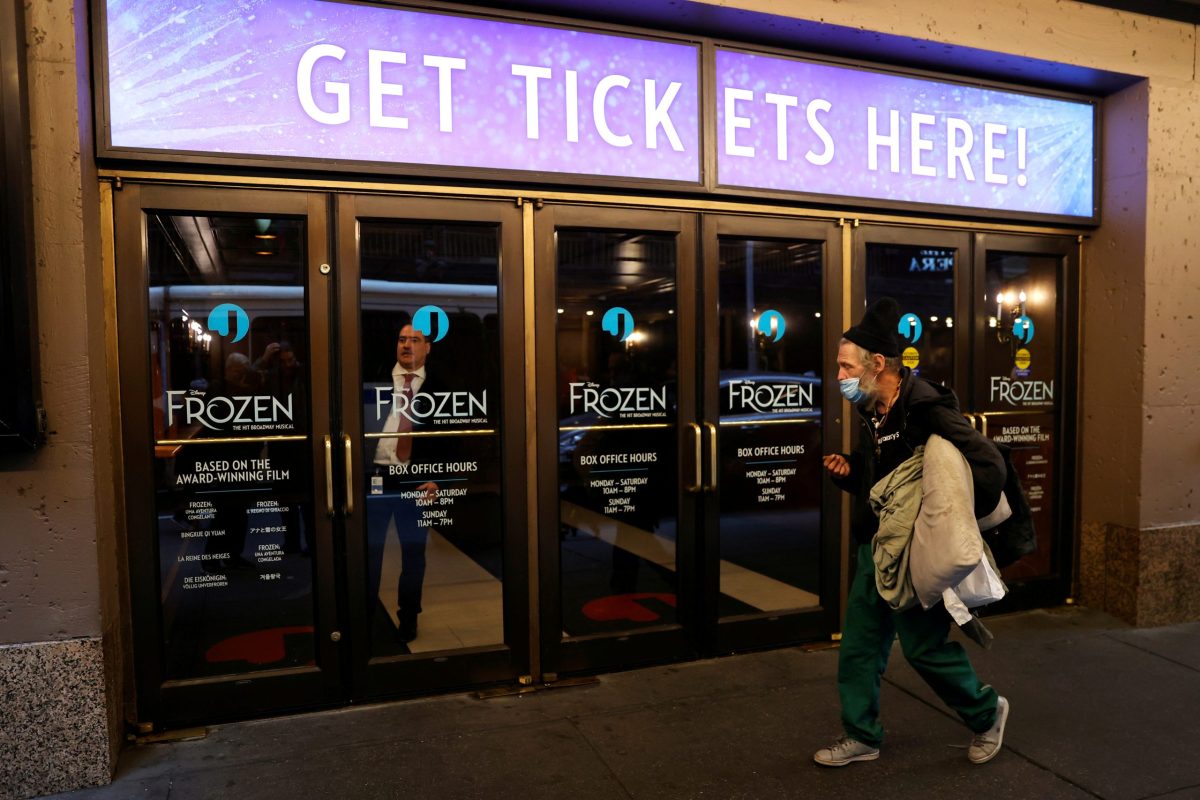 FILE PHOTO: A man wears a mask as he passes the closed St. James Theatre where the musical “Frozen” plays in New York