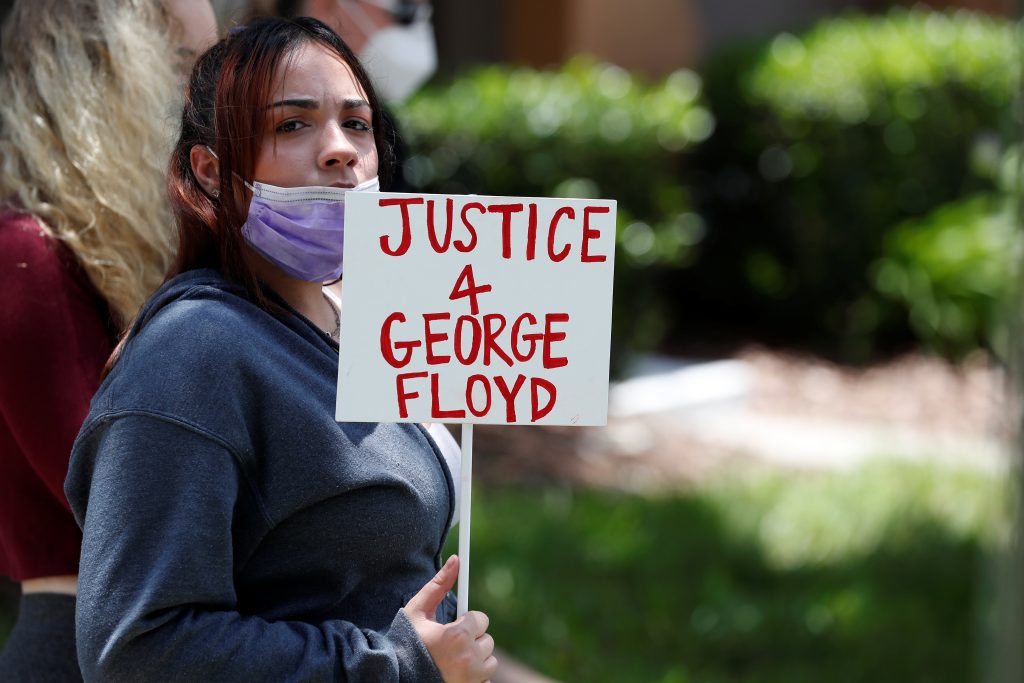 A protester holds a sign outside the Florida home of former Minneapolis police officer Derek Chauvin, in Orlando