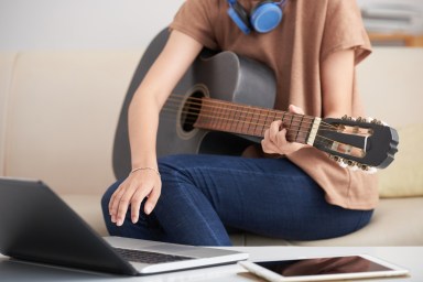 Female with guitar using laptop