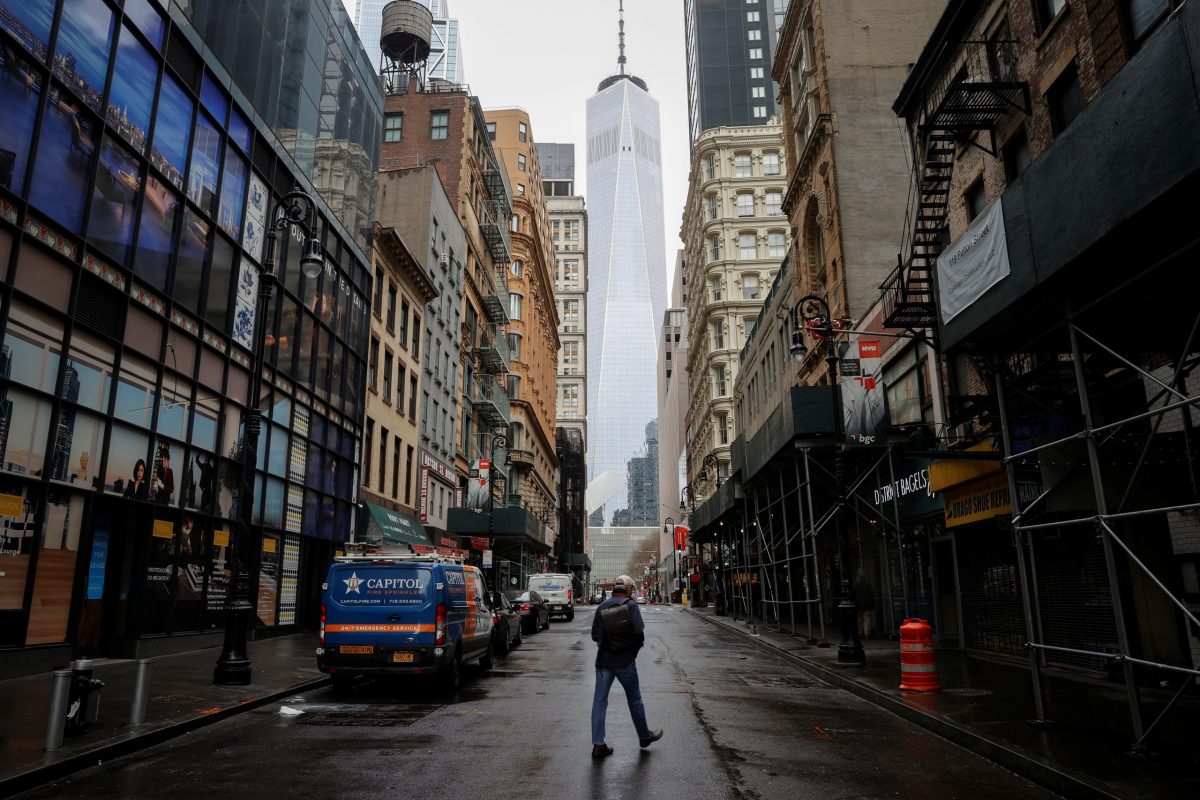 A man crosses a nearly deserted Fulton Street in the financial district of lower Manhattan in New York