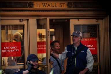 Traders exit the 11 Wall St. door of the NYSE in New York