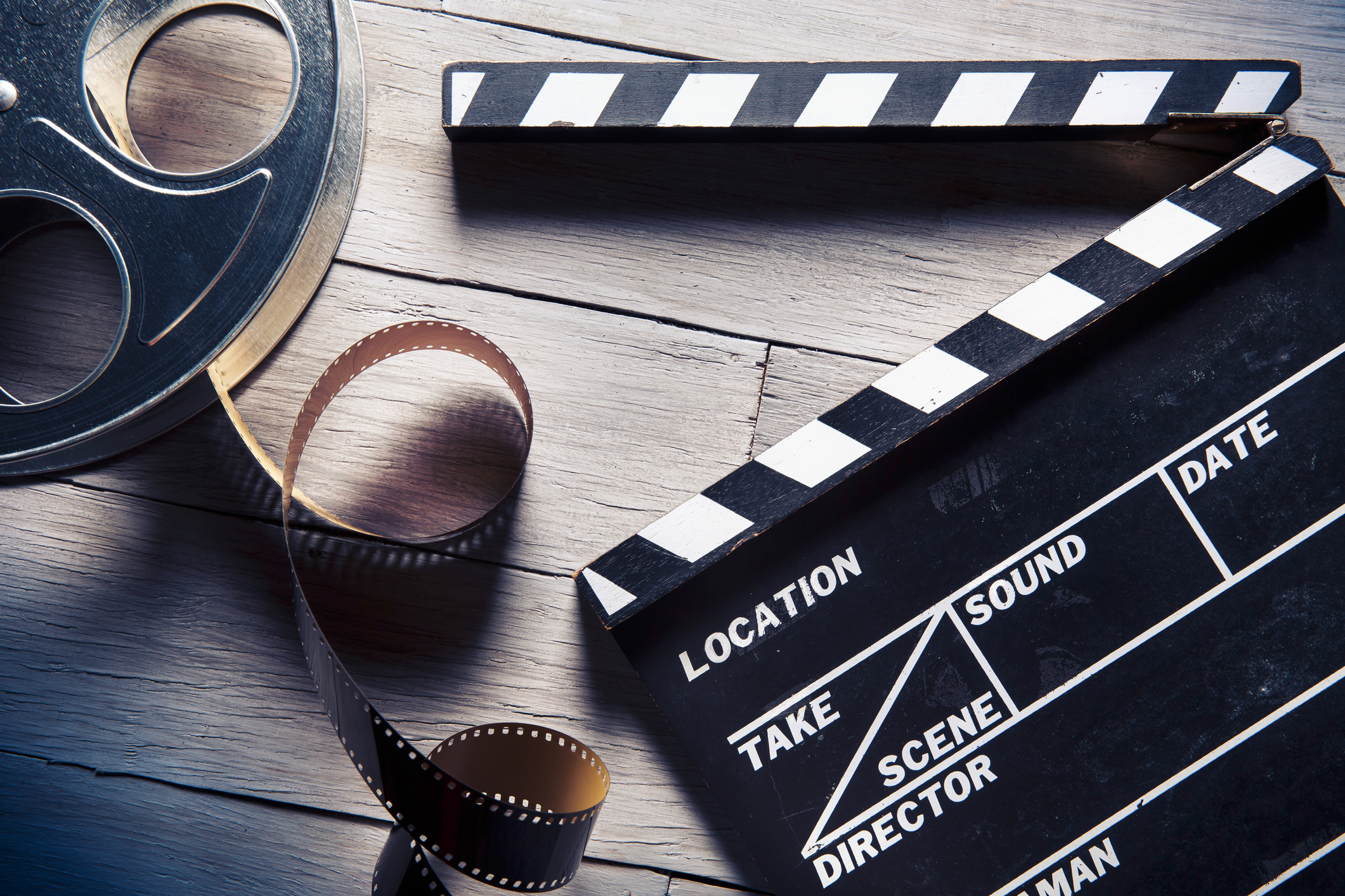 Film reel and movie clapper on wooden background
