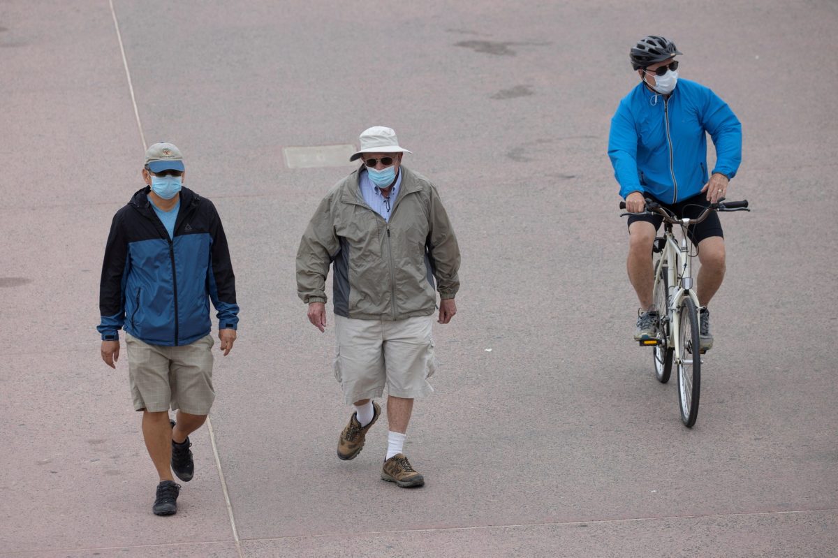FILE PHOTO:  People wear face masks as they use the beach boardwalk during the outbreak of the coronavirus disease (COVID-19), in Huntington Beach, California