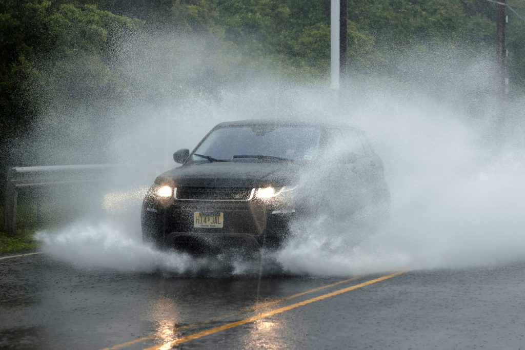A car moves through a partially flooded street as Tropical Storm Fay sweeps across the heavily populated northeastern United States in Jersey City