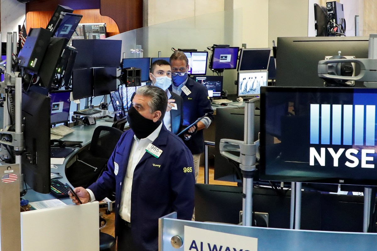 Traders wearing masks work, on the first day of in-person trading since the closure during the outbreak of the coronavirus disease (COVID-19) on the floor at the NYSE in New York